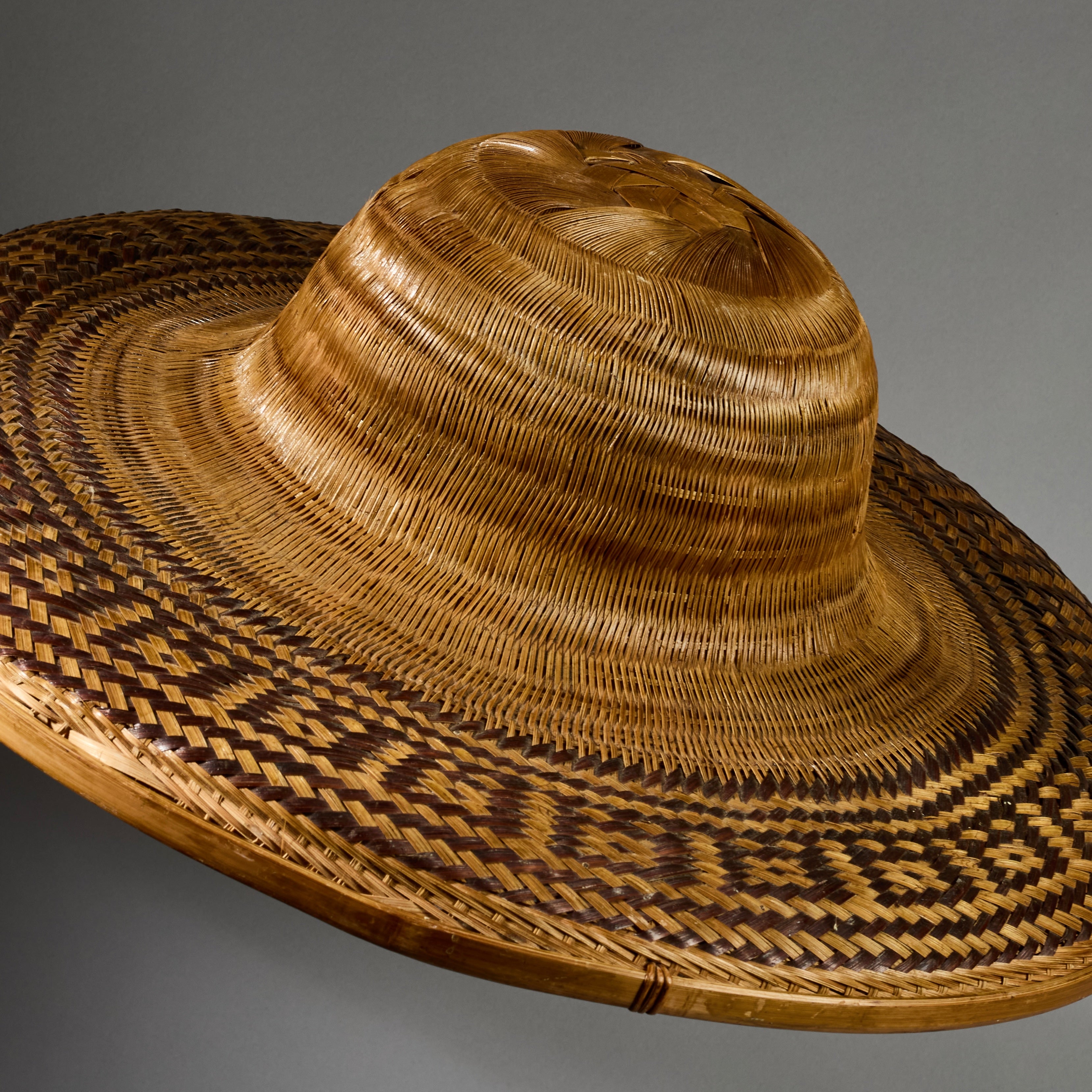 A VINTAGE LARGE WOVEN SUN HAT WITH DECORATIVE FLOURISH, FROM INDONESIA