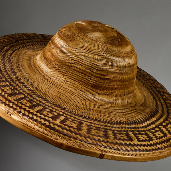 A VINTAGE LARGE WOVEN SUN HAT WITH DECORATIVE FLOURISH, FROM INDONESIA
