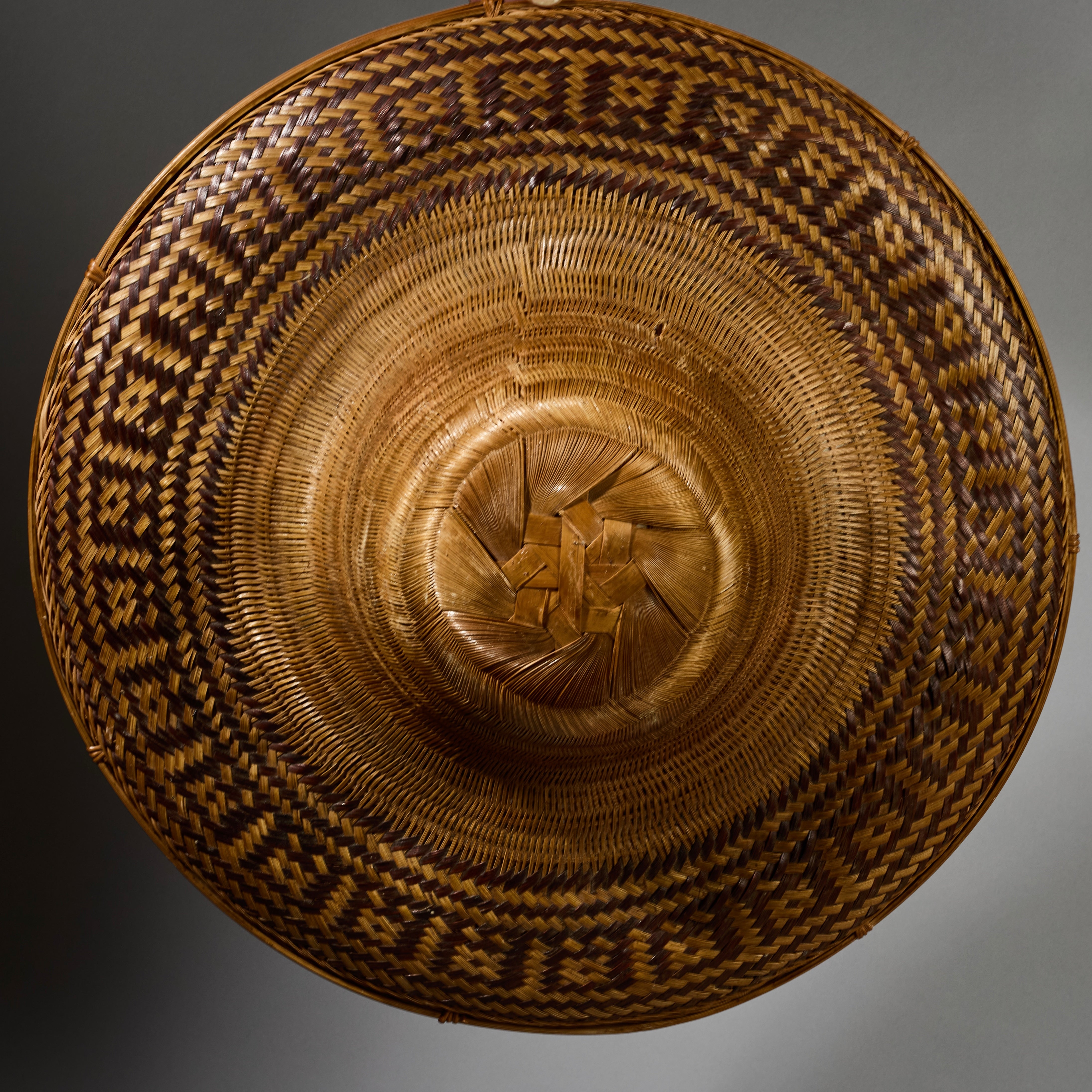 A VINTAGE LARGE WOVEN SUN HAT WITH DECORATIVE FLOURISH, FROM INDONESIA